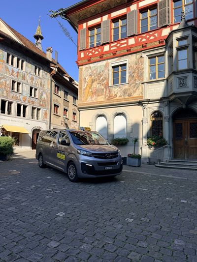 Bahnhofsgebäude mit einem davor geparkten Taxi.