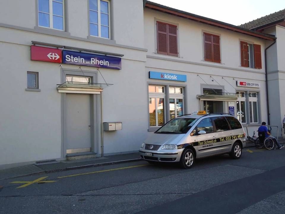 Bahnhofsgebäude mit einem davor geparkten Taxi.