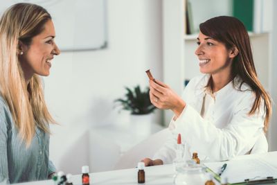 Bunte Pillenfläschchen verschütten weisse Tabletten auf eine Holzoberfläche.