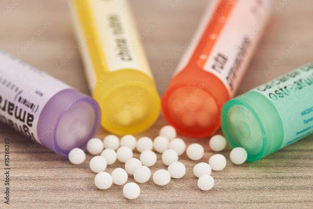 Bunte Pillenfläschchen verschütten weisse Tabletten auf eine Holzoberfläche.
