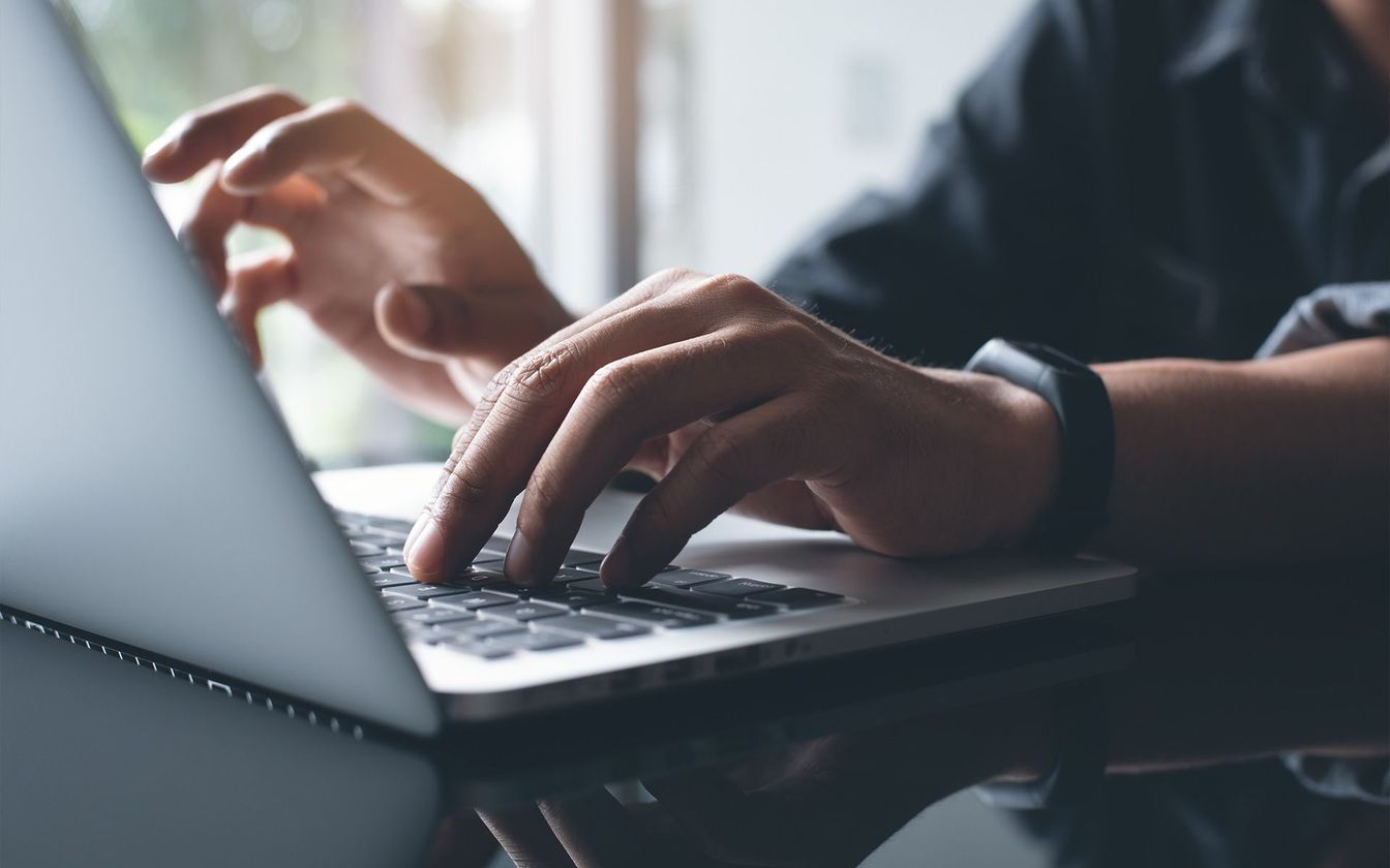 Main posée sur le clavier d'un ordinateur portable