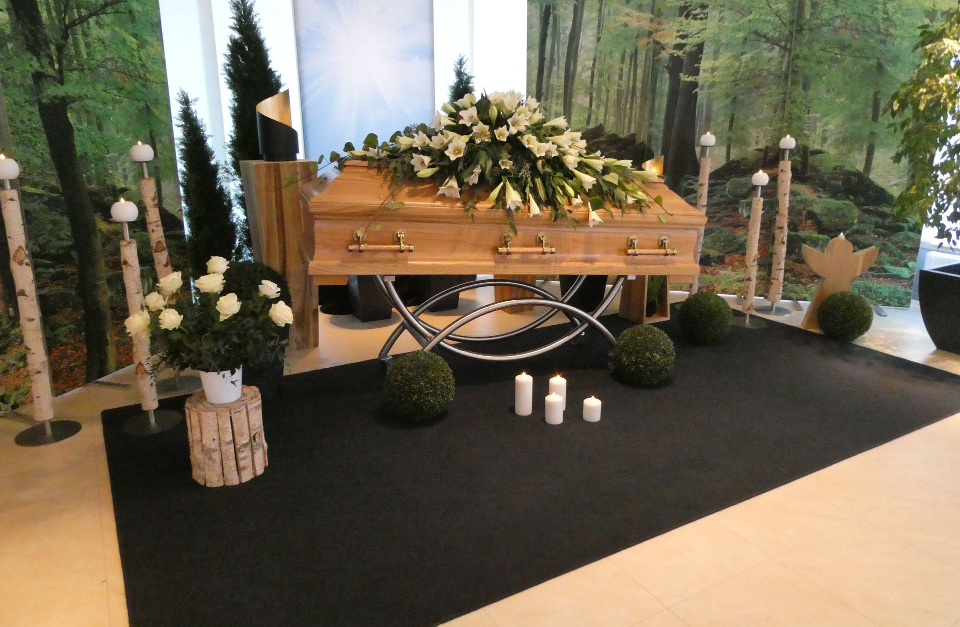 Ein mit Blumen bedeckter Holzsarg in einer Trauerkapelle mit Kerzen und weißen Blumenarrangements