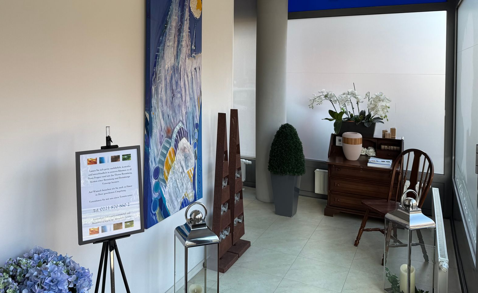 Büro-Pausenraum mit rundem Tisch, Stühlen, Küchenzeile und großen Fenstern mit Jalousien.