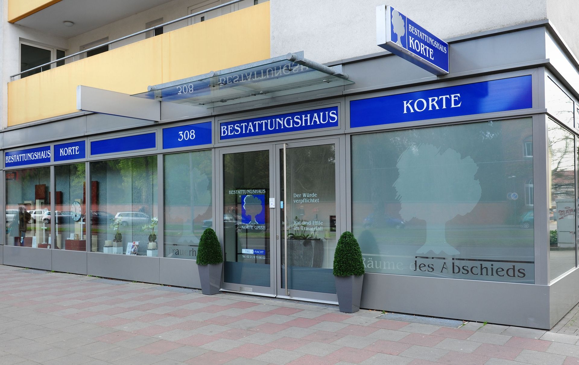 Schaufenster mit blauer Beschilderung und großen Glasfenstern an einem städtischen Bürgersteig