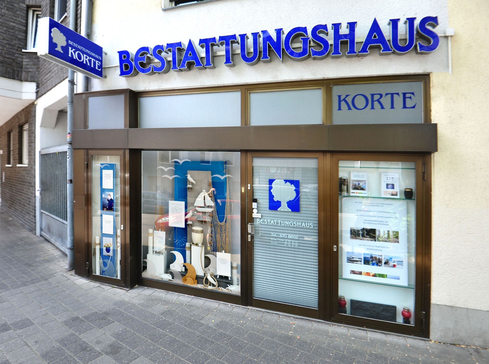 Außenansicht eines blau-beigen Bestattungsinstituts mit der Aufschrift BESTATTUNGSHAUS KORTE