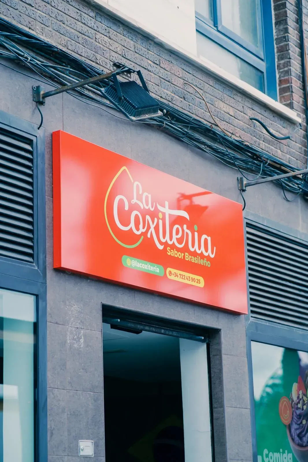 Letrero rojo y blanco del restaurante La Coxiteria encima de una puerta.