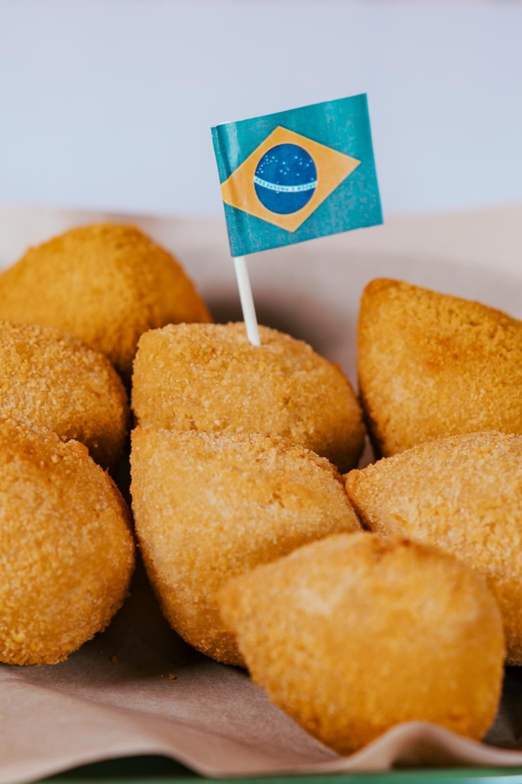 Risoles brasileños dorados y fritos con una bandera de Brasil en un palillo.