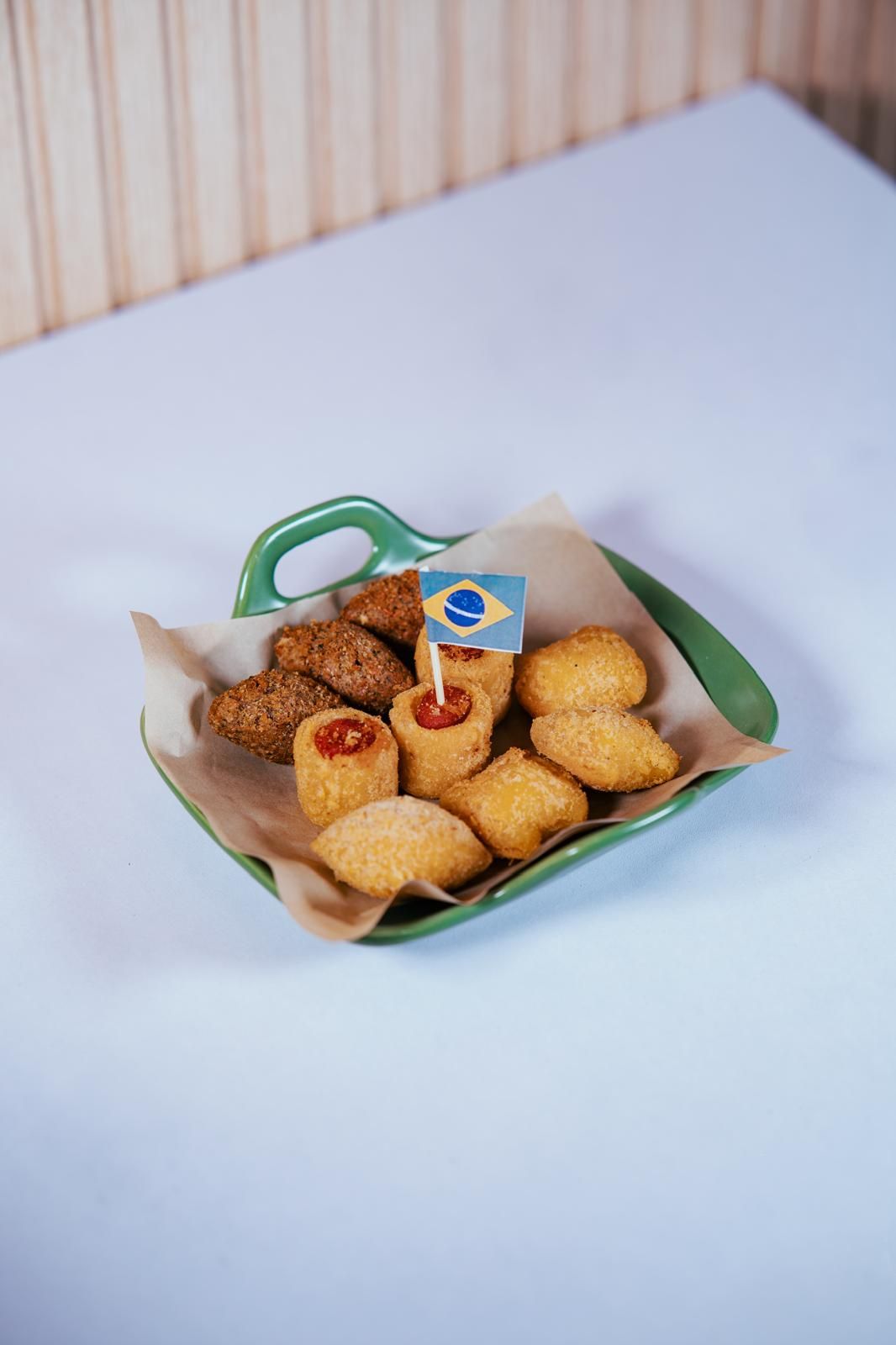 Un plato de bocadillos brasileños fritos con un palillo con la bandera de Brasil.