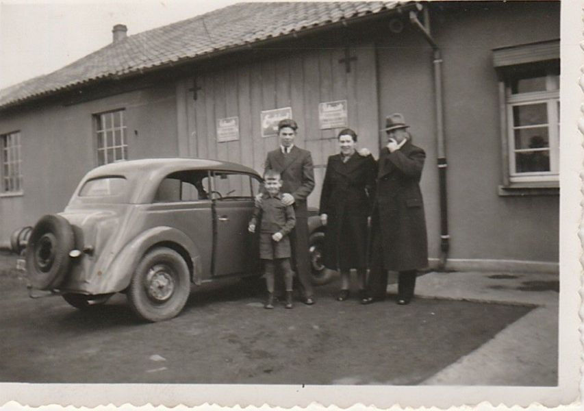 Ein Schwarzweißfoto einer Familie, die vor einem Auto steht