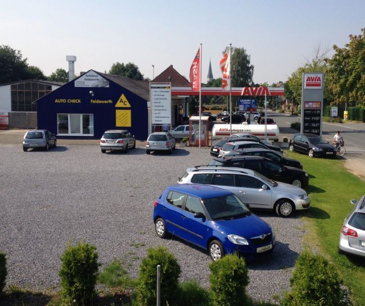 Viele Autos sind vor einem Gebäude geparkt, auf dem Autocheck steht