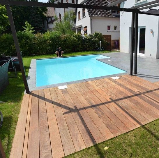 Piscine encastrée dans une terrasse bois et carrelage.