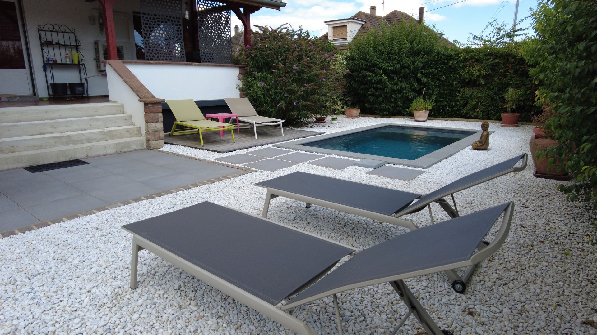 Transats sur des cailloux près d'une piscine.