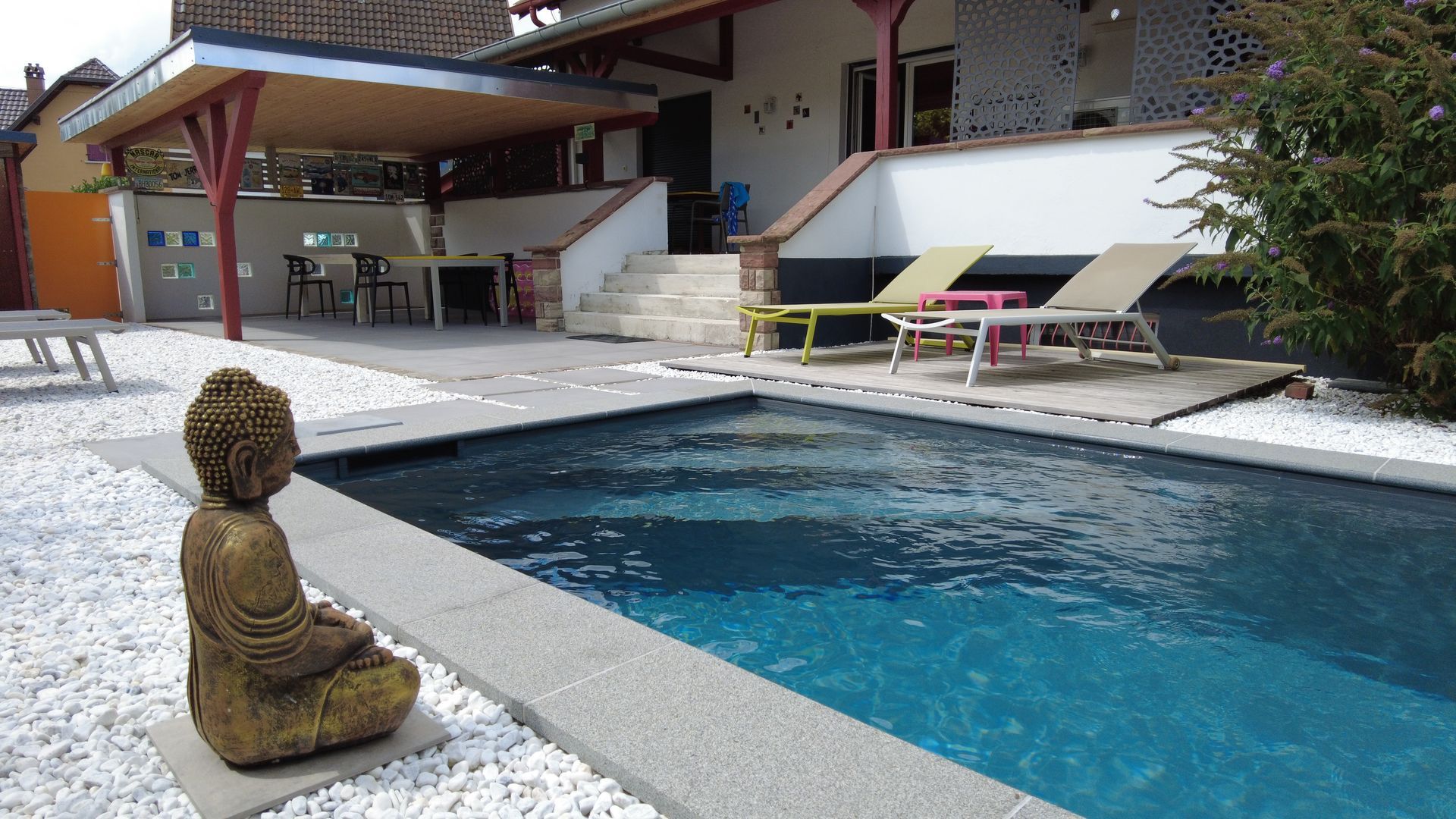 Statue d'un bouddha près d'une piscine avec margelle en béton.