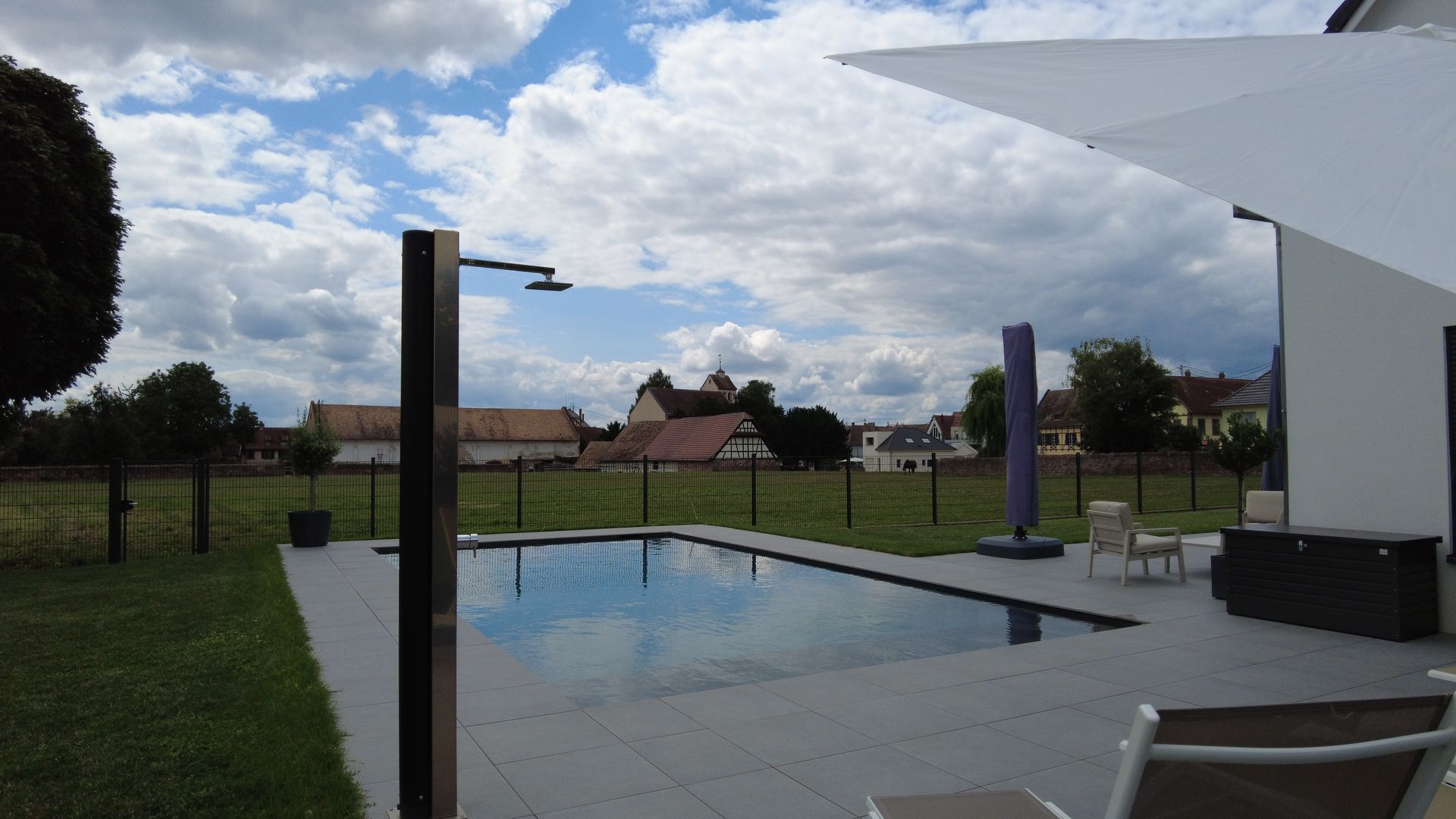 Piscine en béton près d'un terrain clôturé.