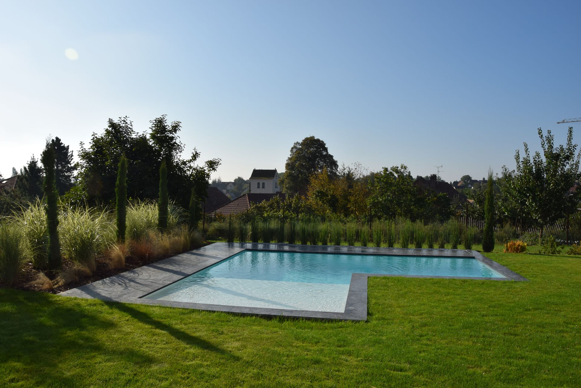Piscine en L dans le coin d'un jardin.
