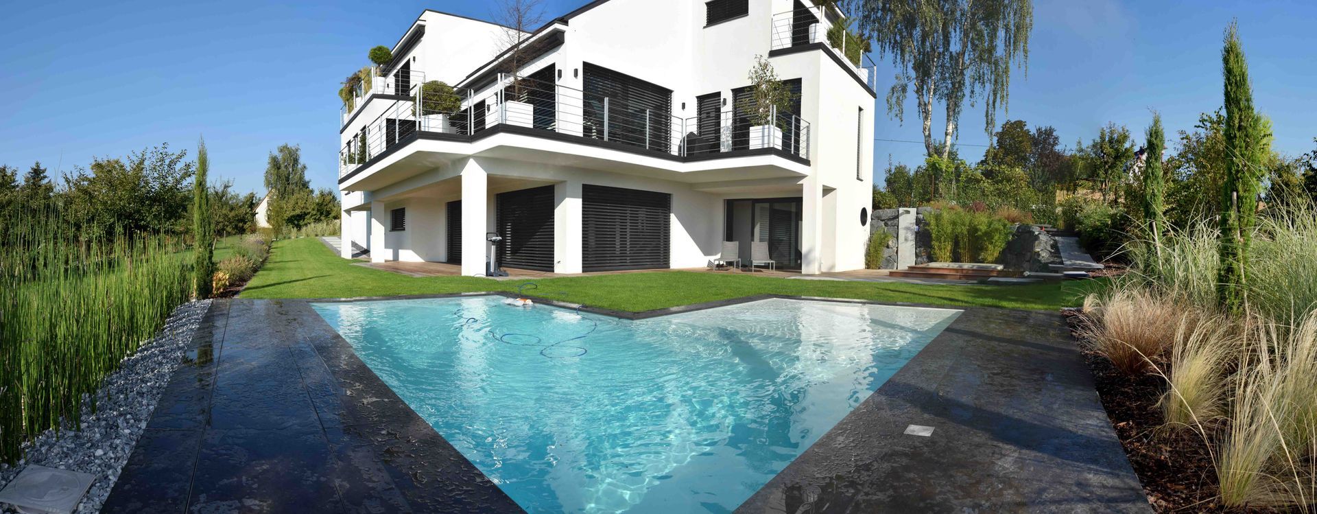 Grande piscine d'une maison moderne blanche.