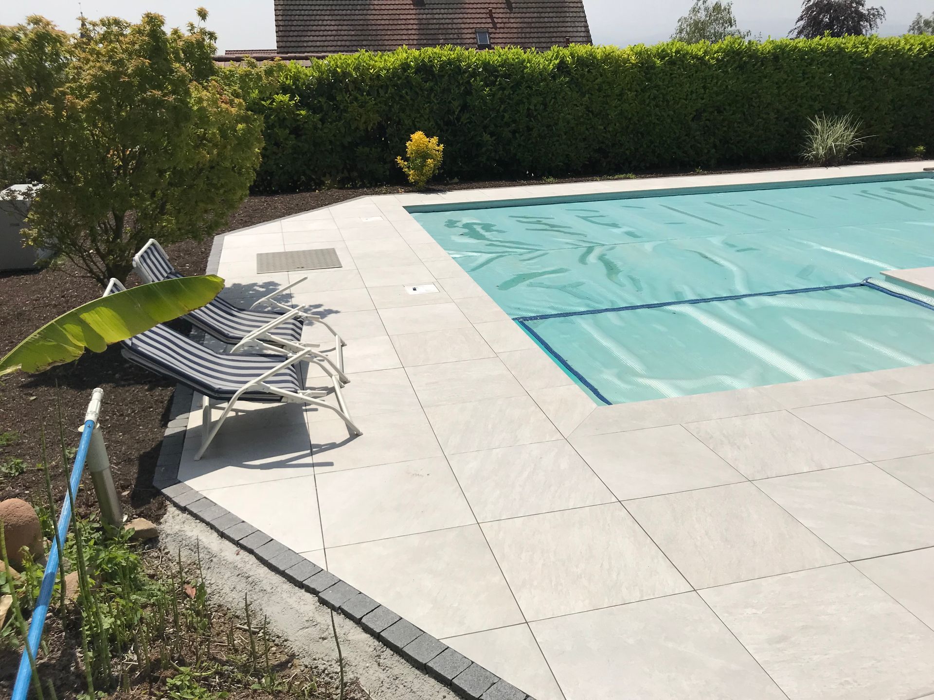 Terrasse d'une piscine couverte d'une bâche claire.