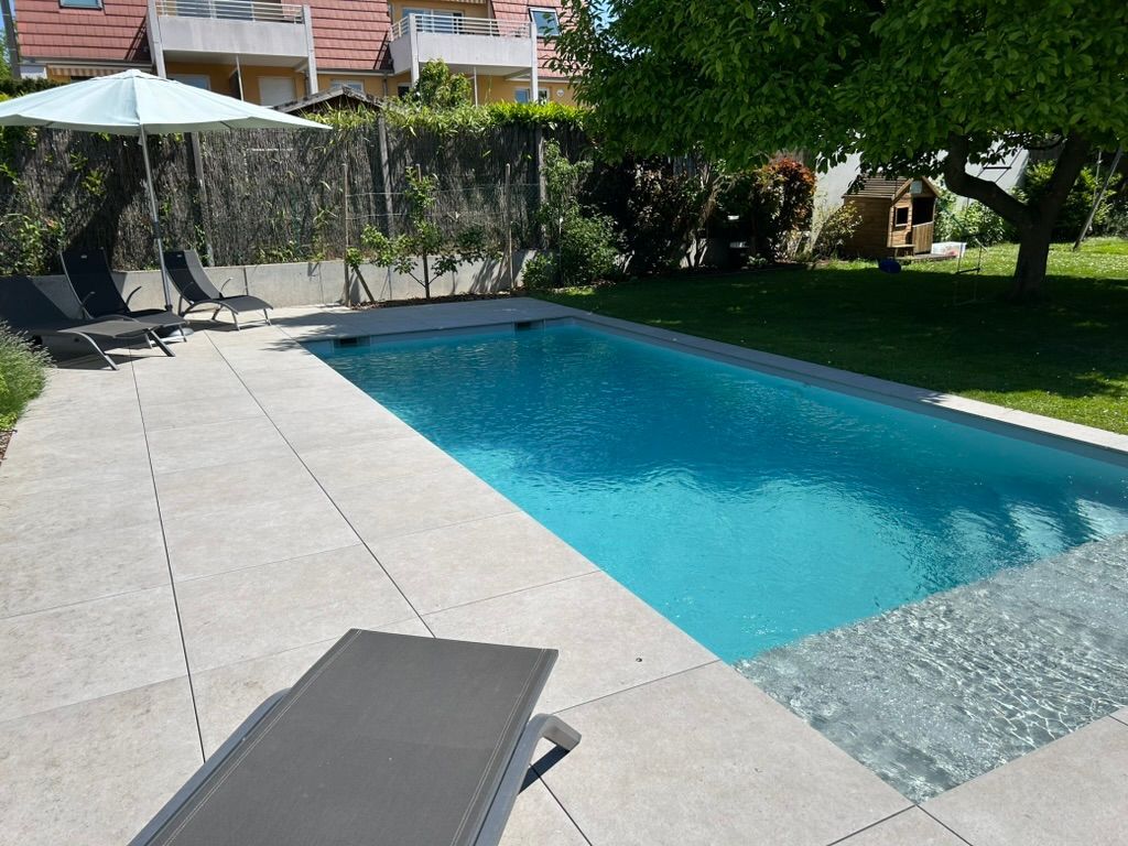 Piscine avec terrasse béton à l'eau claire.
