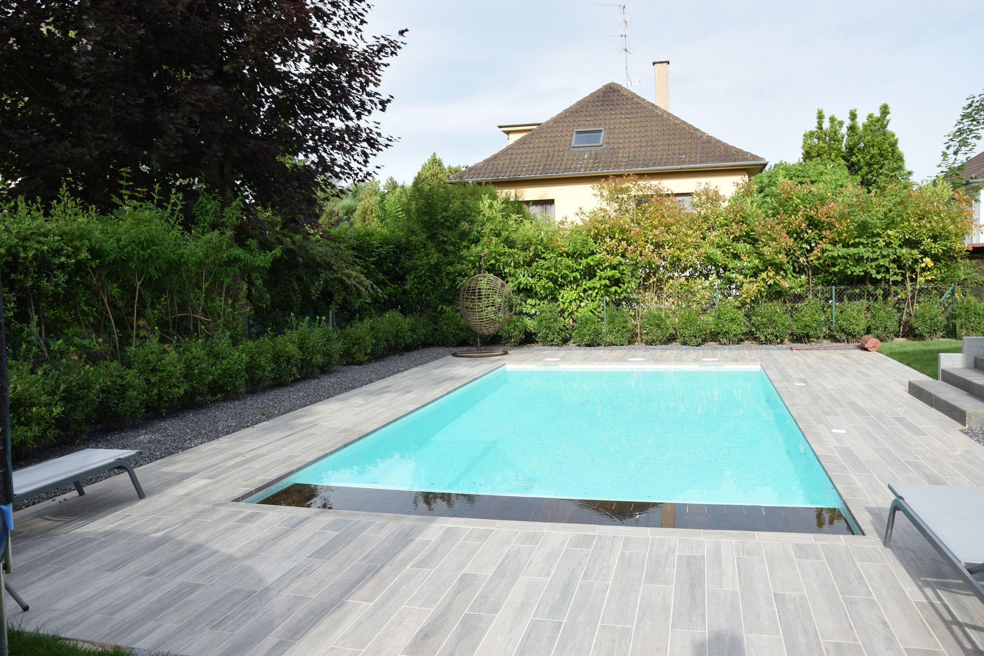 Piscine avec terrasse carrelée en béton et des transats pour se détendre.