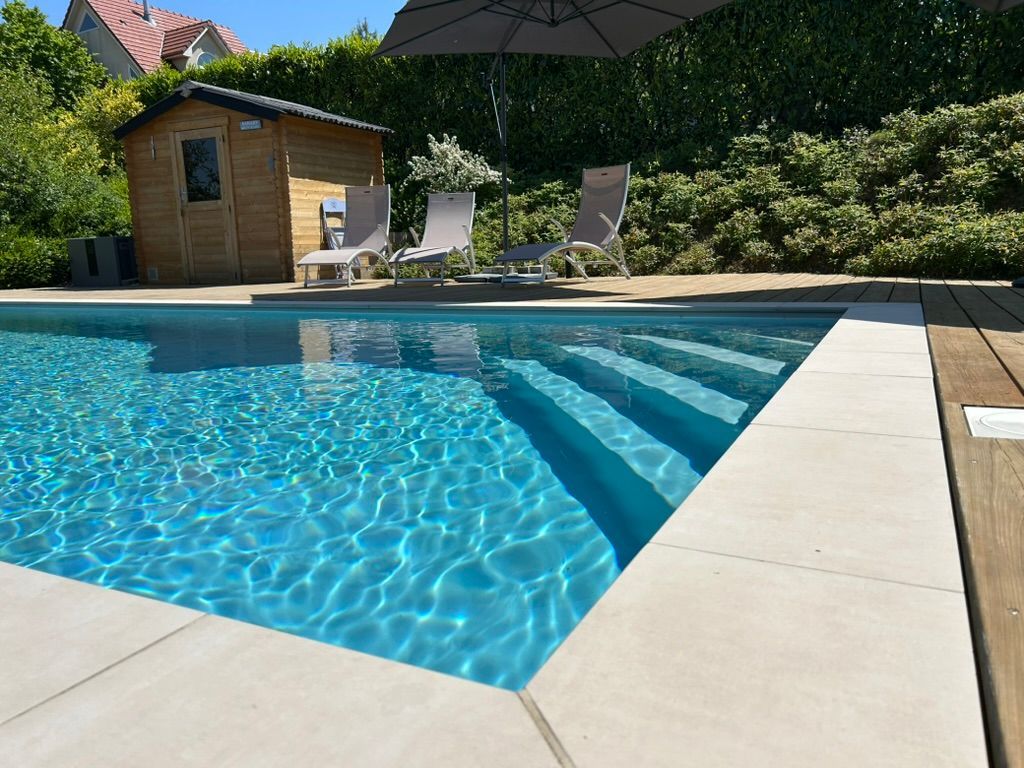 Piscine à coque avec margelles et terrasse en bois.