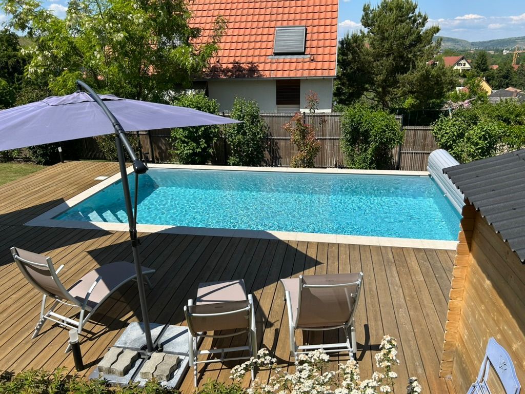 Piscine avec terrasse en bois et trois transats.