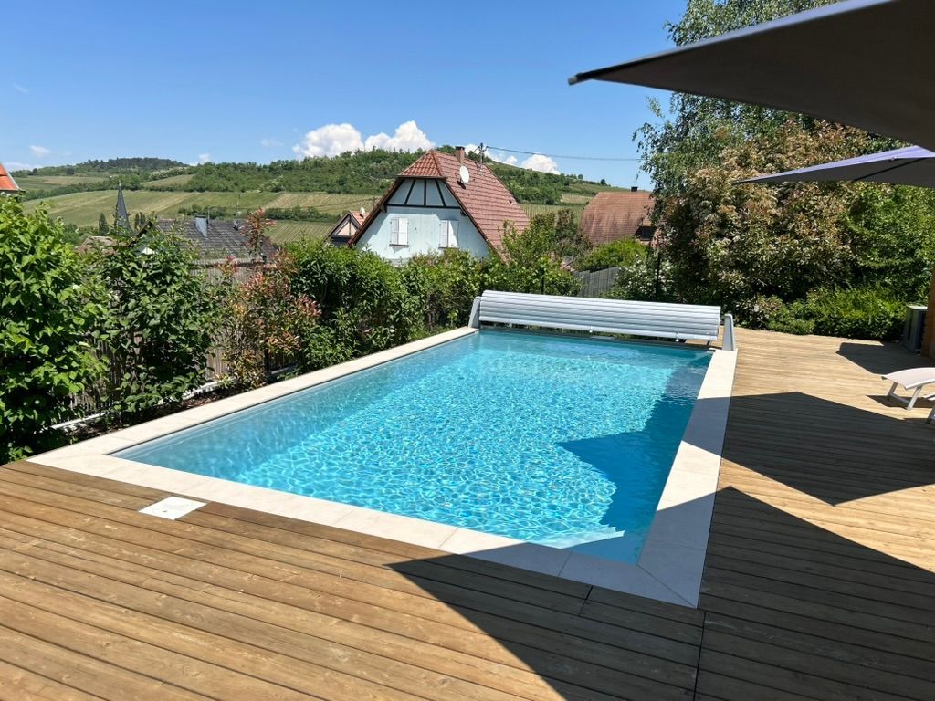 Piscine encastrée dans une terrasse en bois dans un village de campagne.