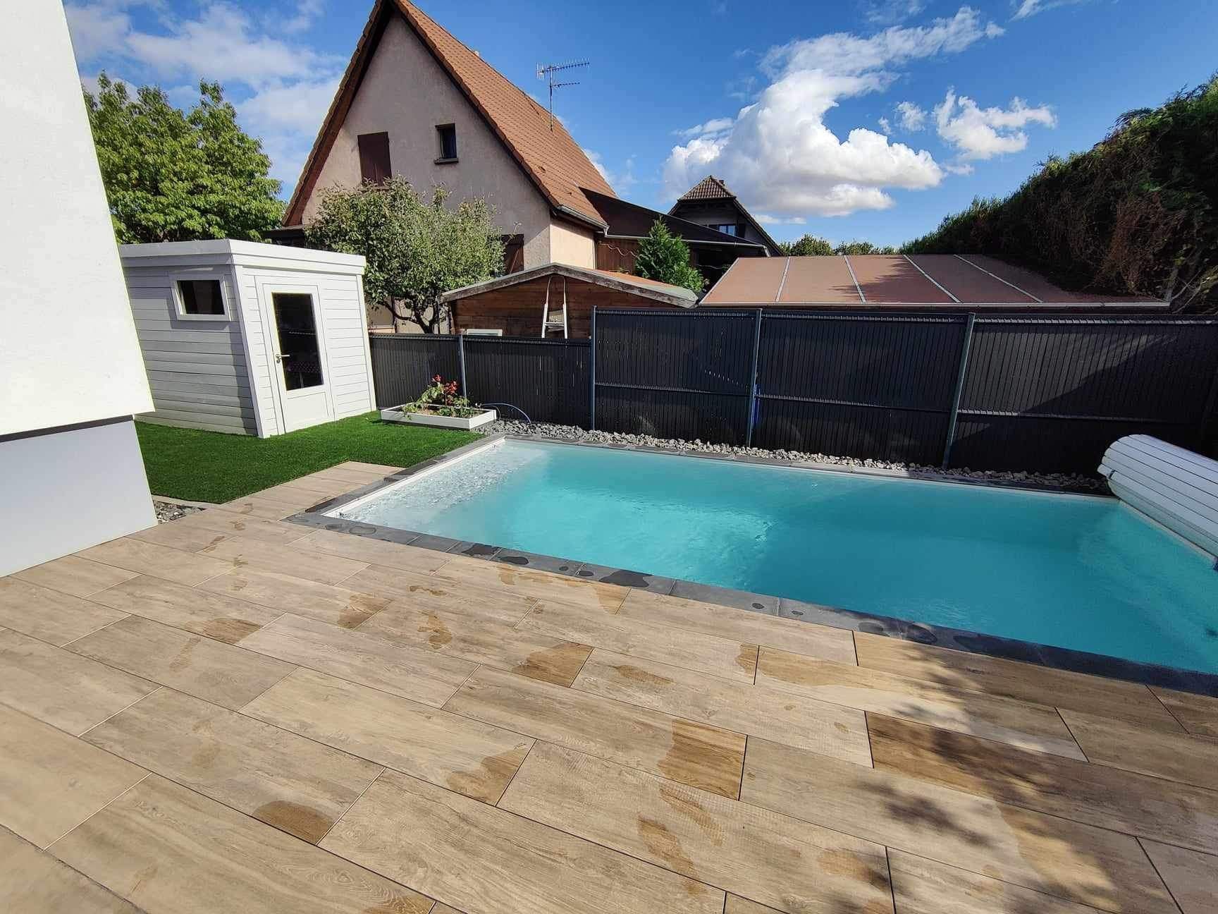 Piscine avec volet roulant à proximité d'une clôture.