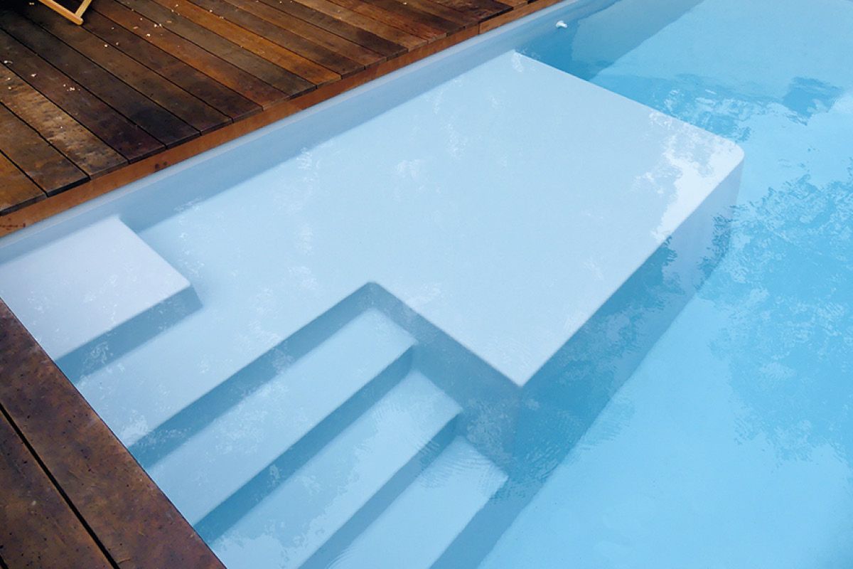 Piscine avec plage et terrasse en bois.