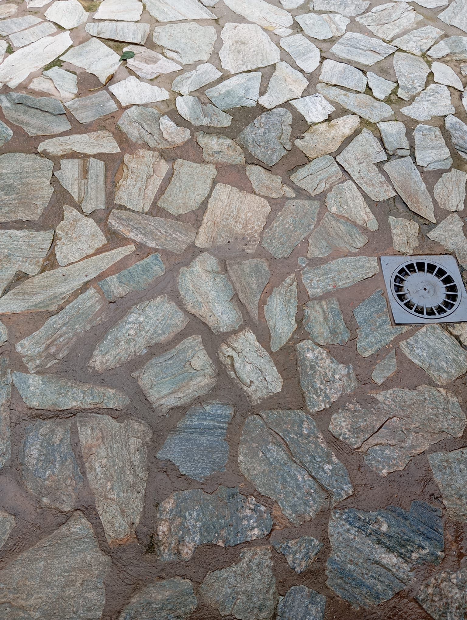 Un primer plano de un camino de piedra con un desagüe en el medio.