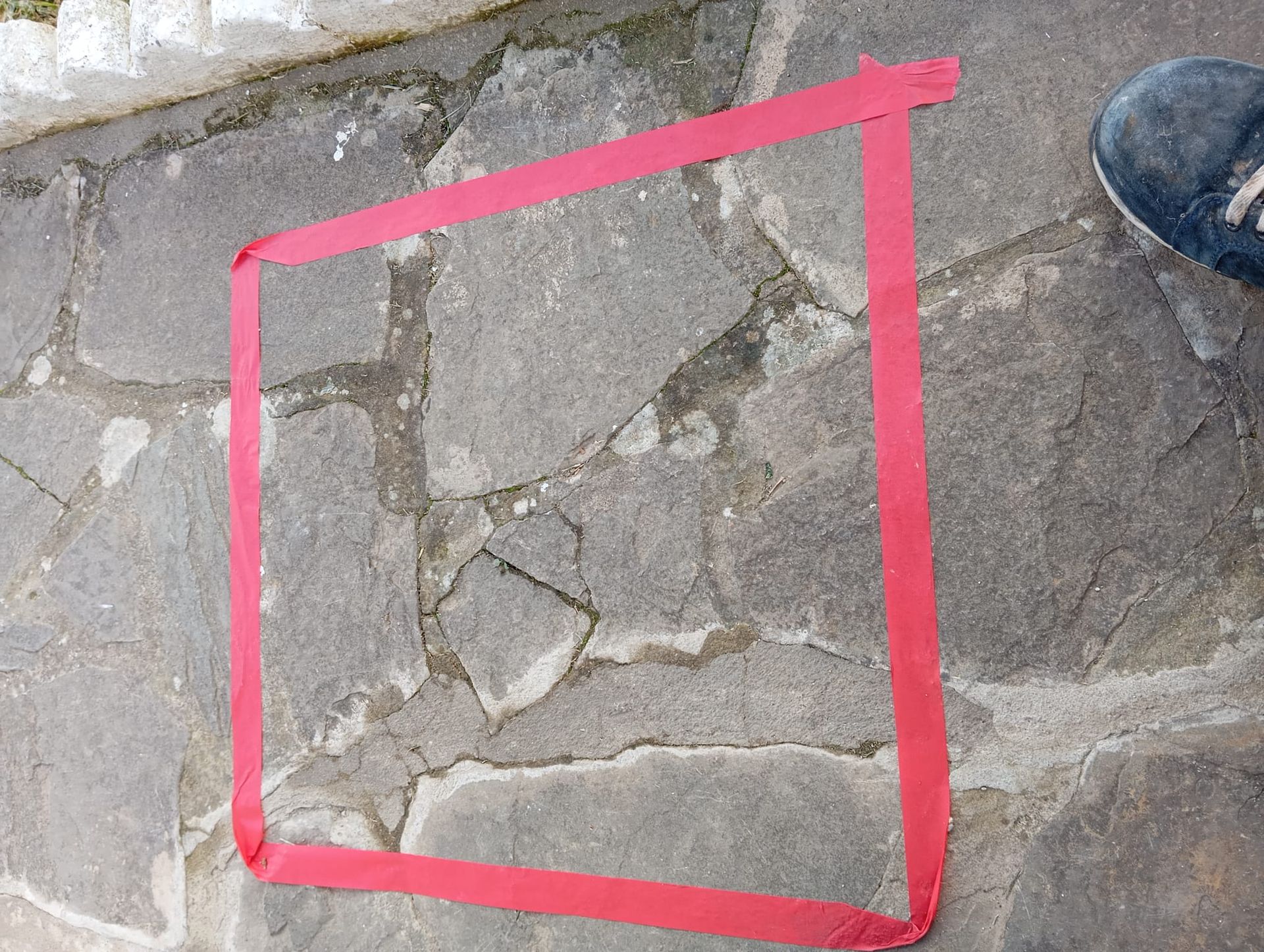 Se utiliza una cinta roja para marcar un cuadrado en un suelo de piedra.