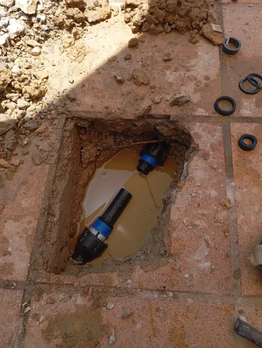 Un lugar de reparación en el suelo con dos secciones expuestas de tubería negra equipadas con acoplamientos