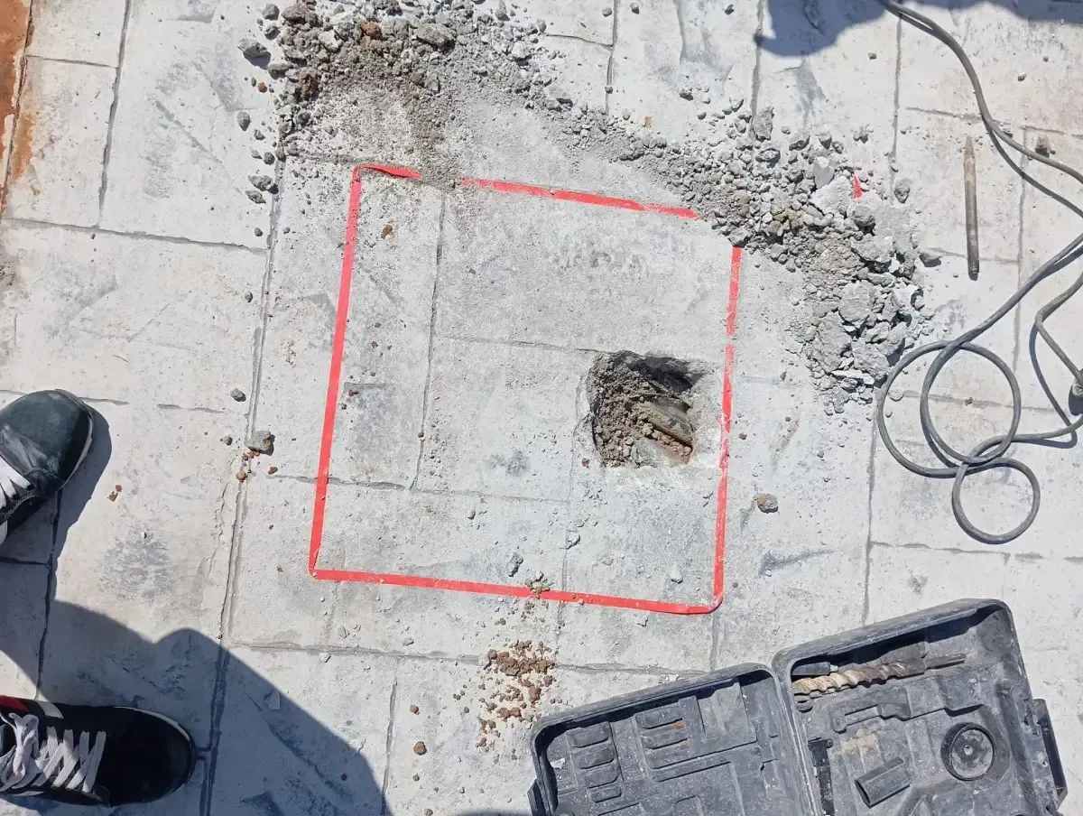Una superficie de hormigón marcada con un cuadrado rojo y un pequeño agujero excavado