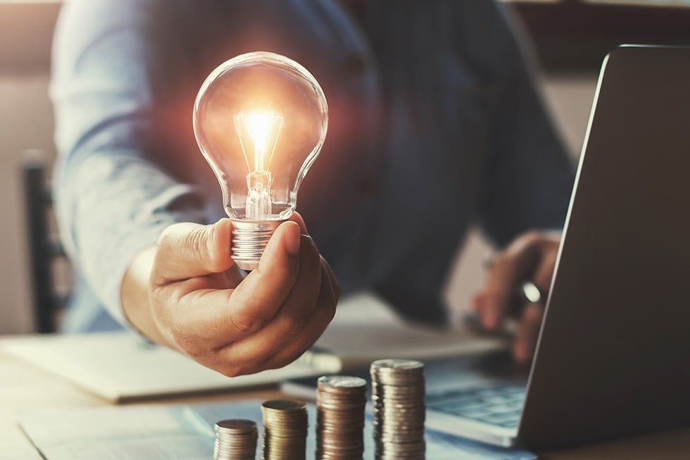 main d'homme tenant une ampoule éclairant de l'argent