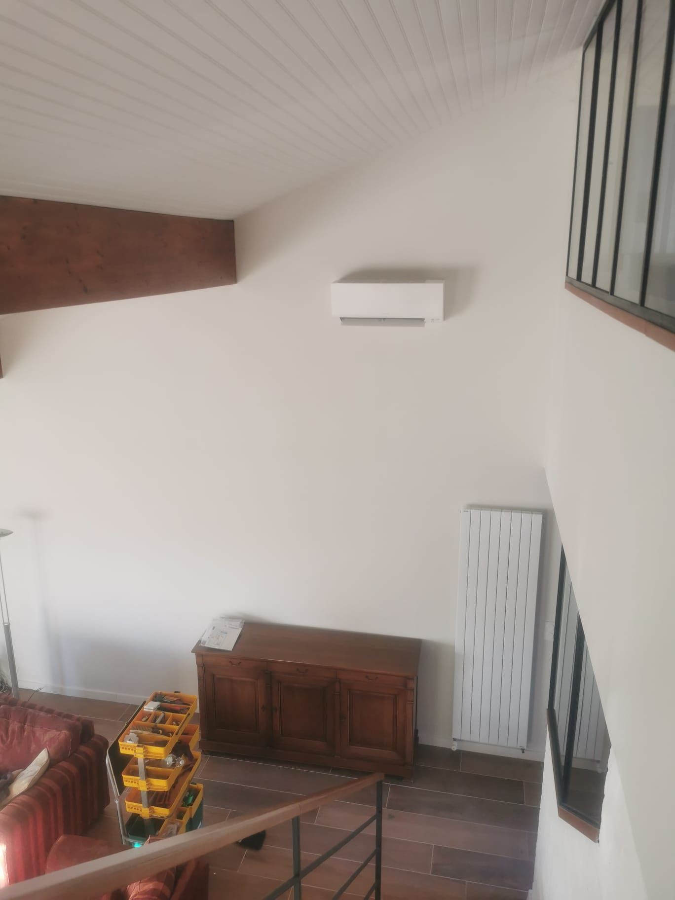 climatisation monosplit installée en hauteur contre un mur blanc