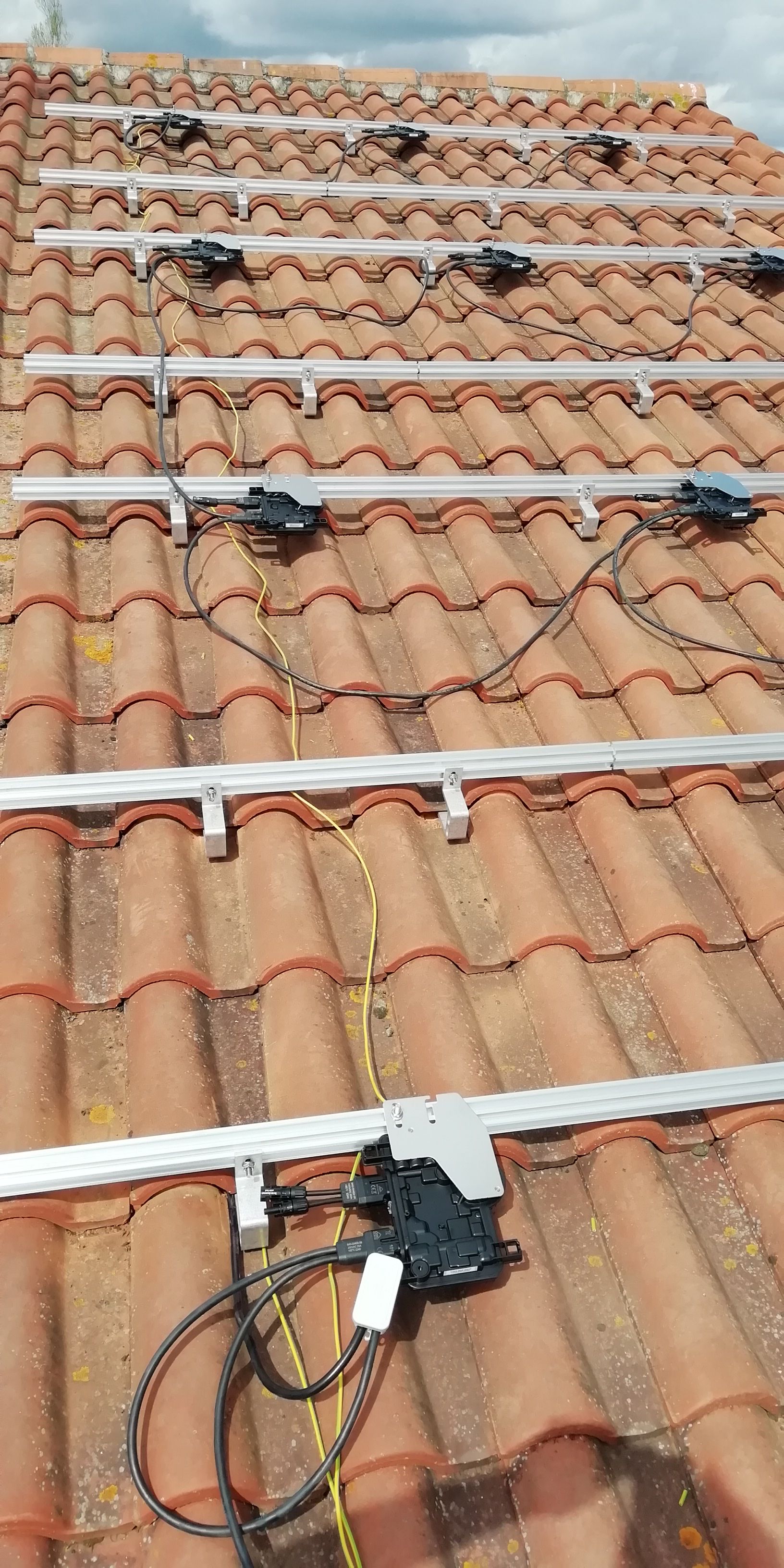 Panneaux solaires installés sur un toit en tuiles rouges.