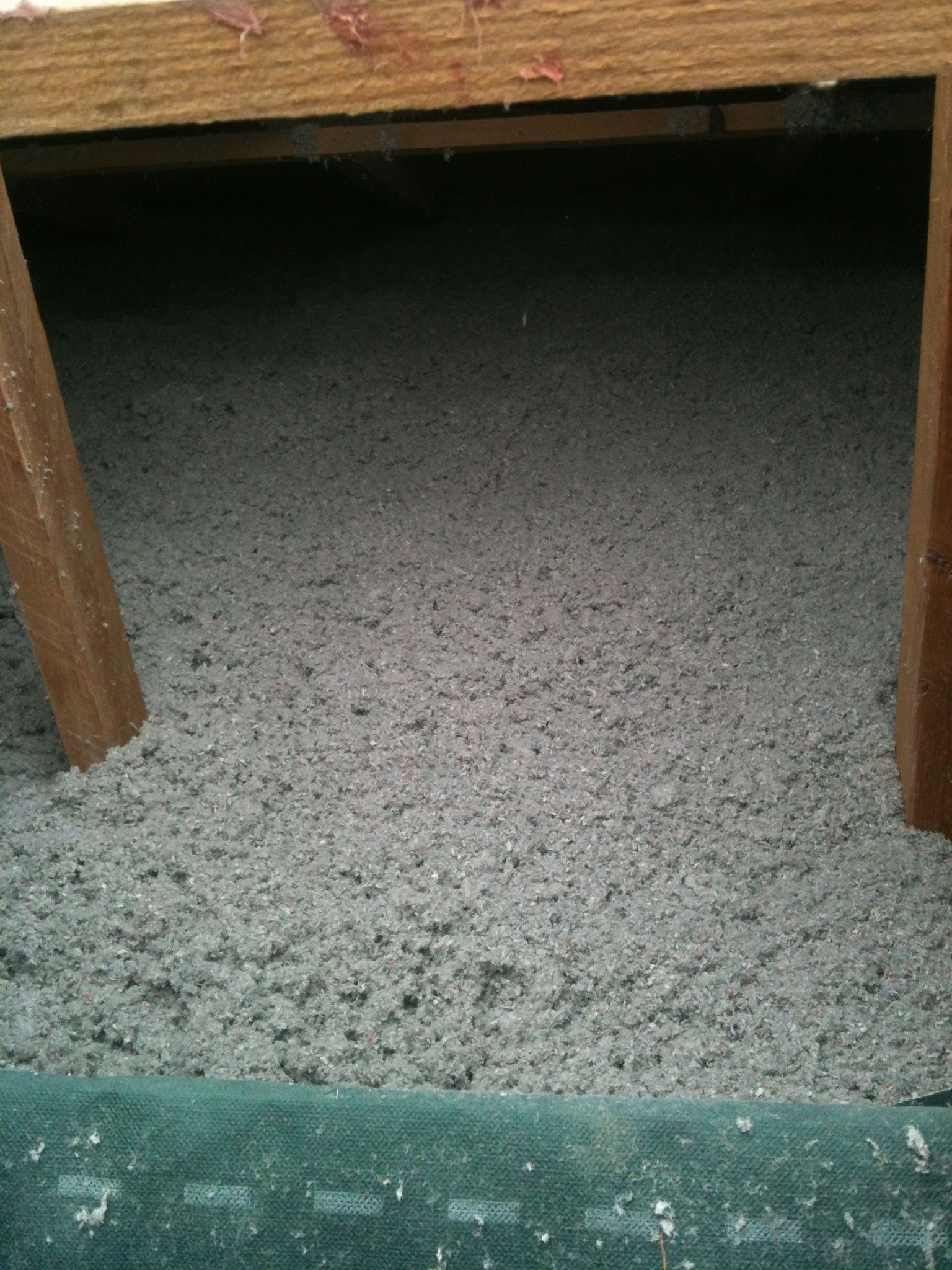 Isolation en cellulose grise entre poutres en bois.