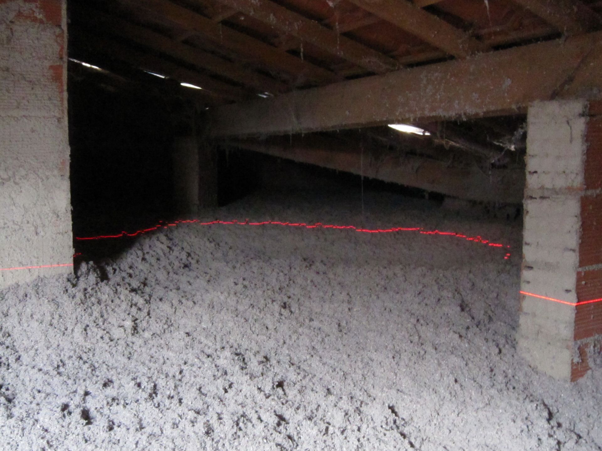 Grenier avec isolation grise ; la ligne laser rouge met en évidence le niveau.