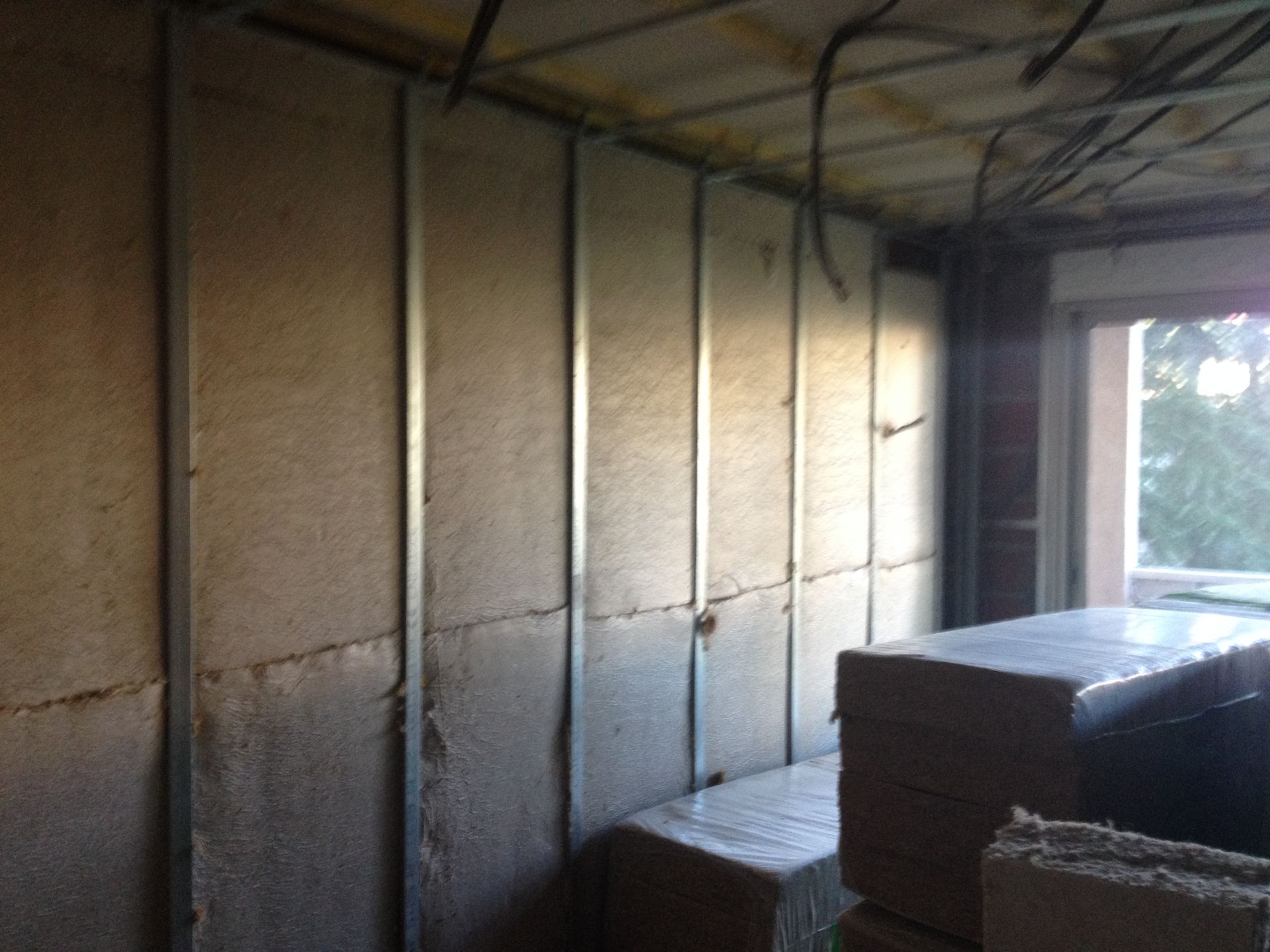 Construction des murs intérieurs en cours : ossature métallique avec isolation. Fenêtre à droite.