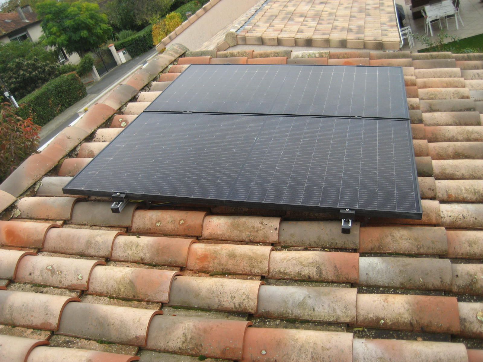 Panneaux solaires installés sur un toit en tuiles rouges.