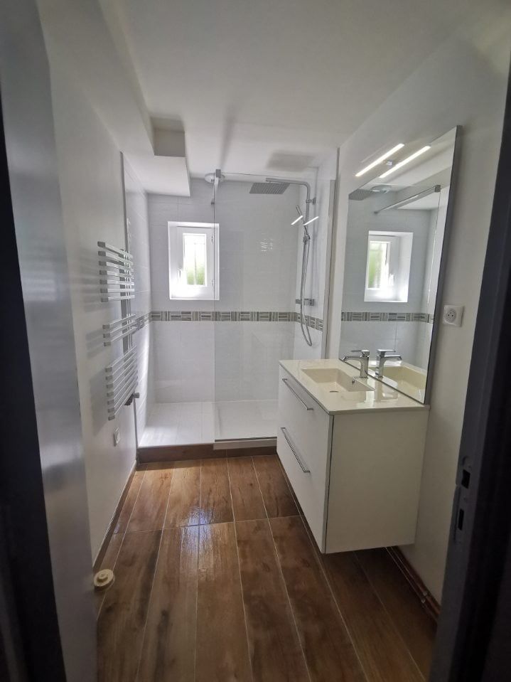 salle de bain moderne avec des meubles blancs et un sol boisé