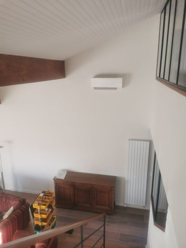climatisation monosplit installée en hauteur entre une poutre et une verrière