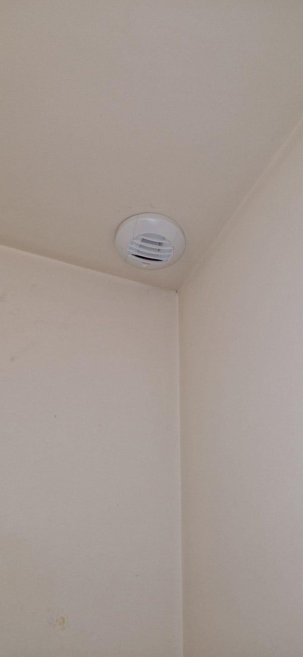 bouche d'aération blanche et arrondie disposée sur un plafond