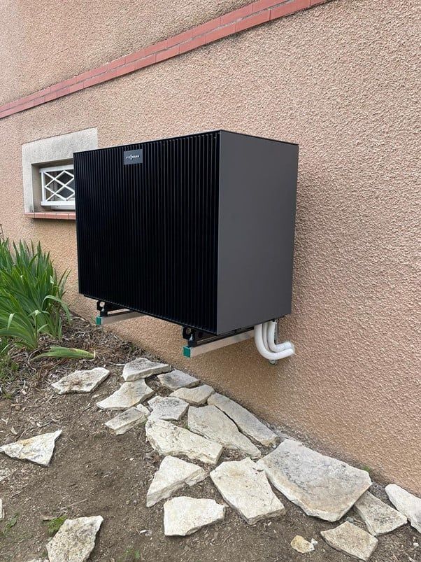 unité extérieure noire installée contre un mur crépi beige