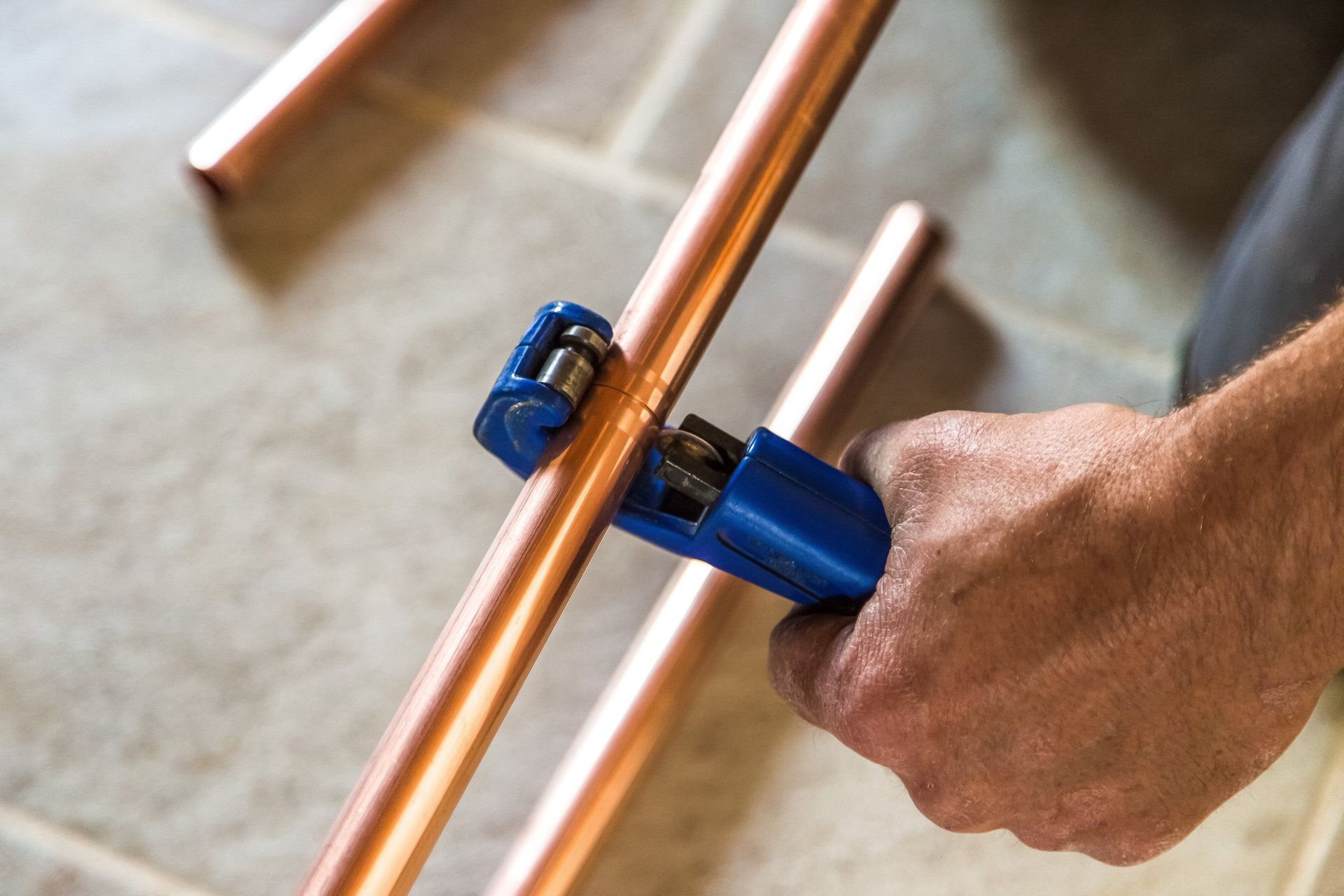 main tenant un outil coupant un tuyau de cuivre