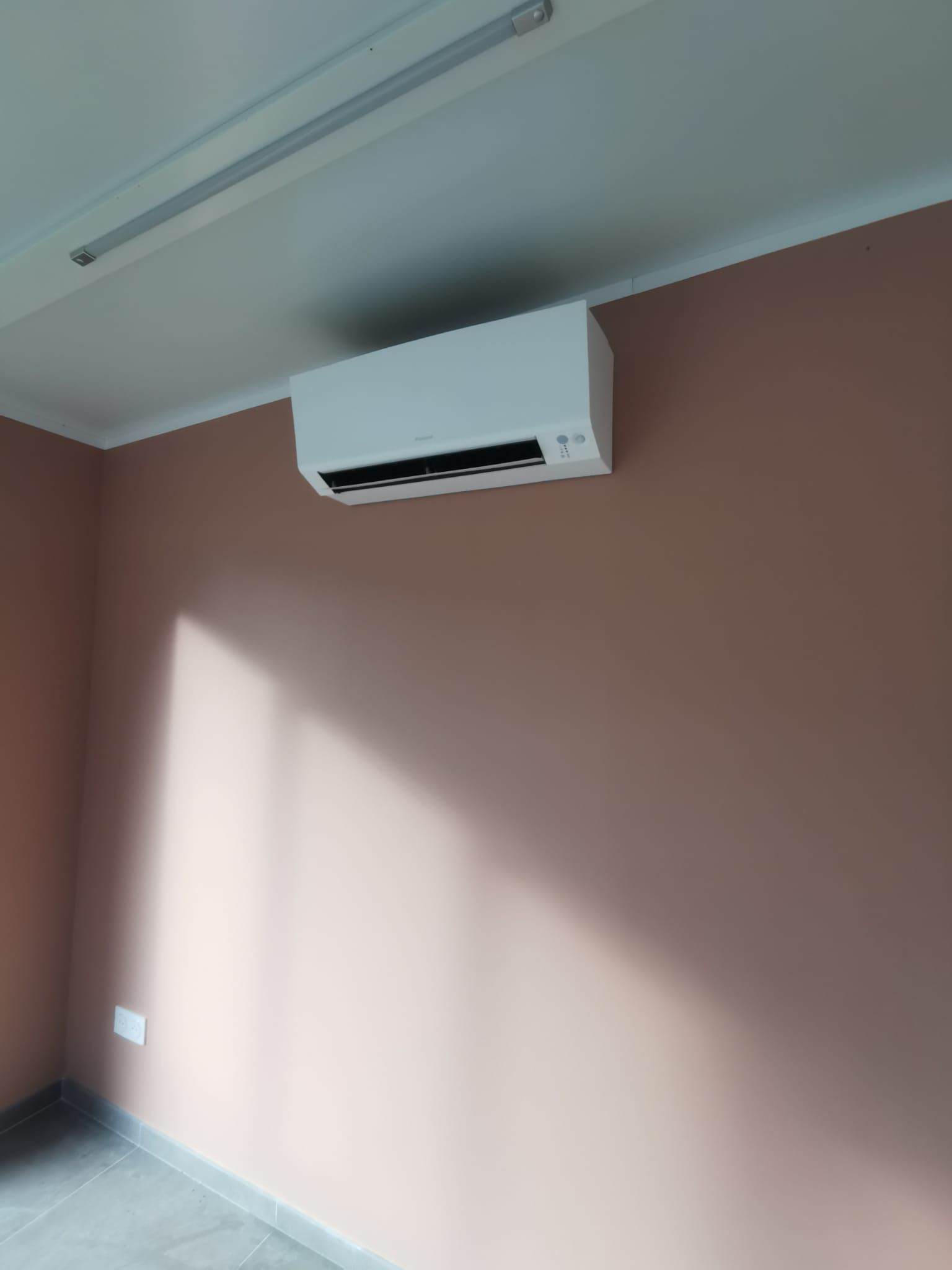 installation d'une climatisation monosplit sur un mur beige