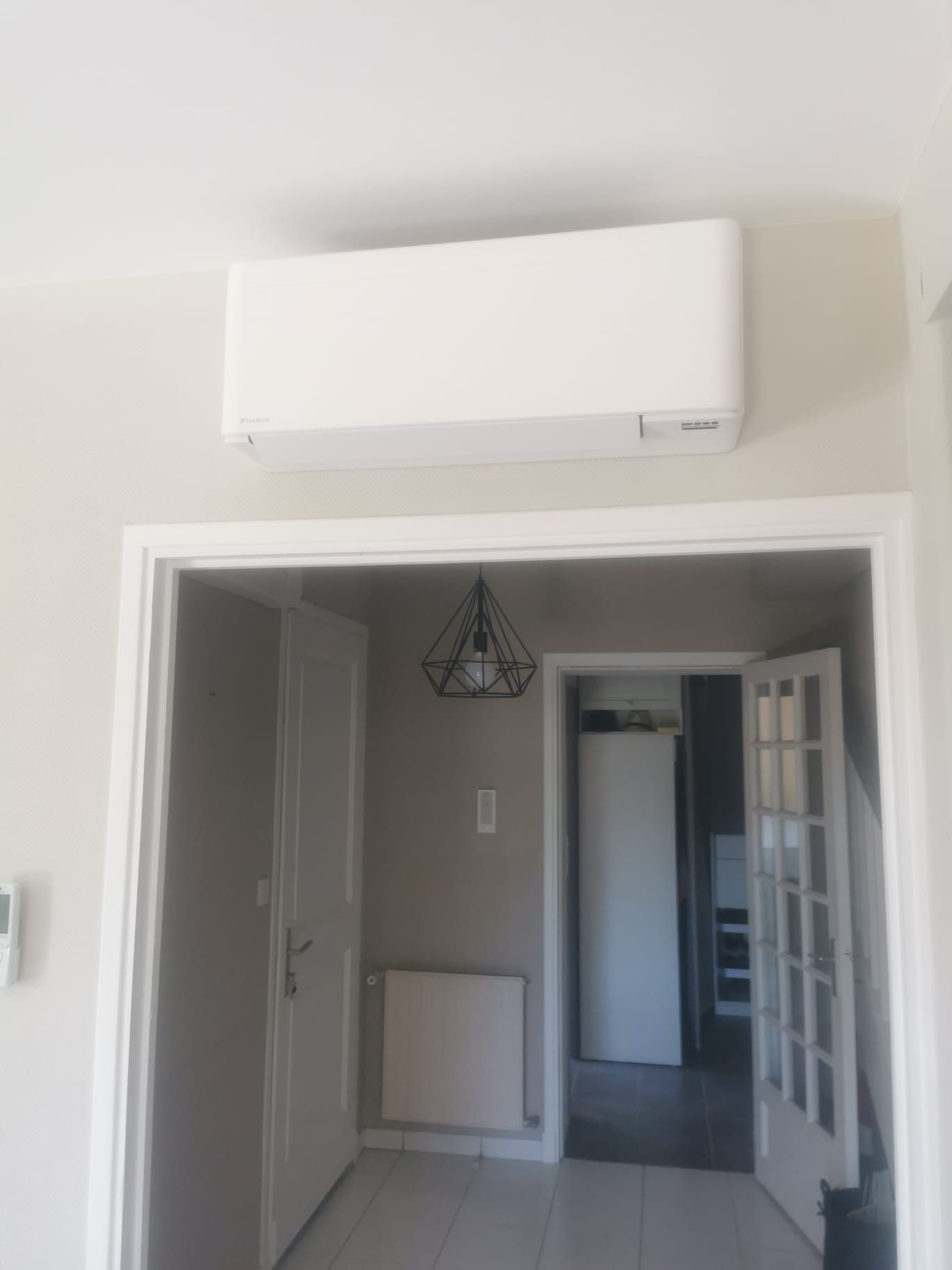 Unité de climatisation blanche montée au-dessus de la porte.