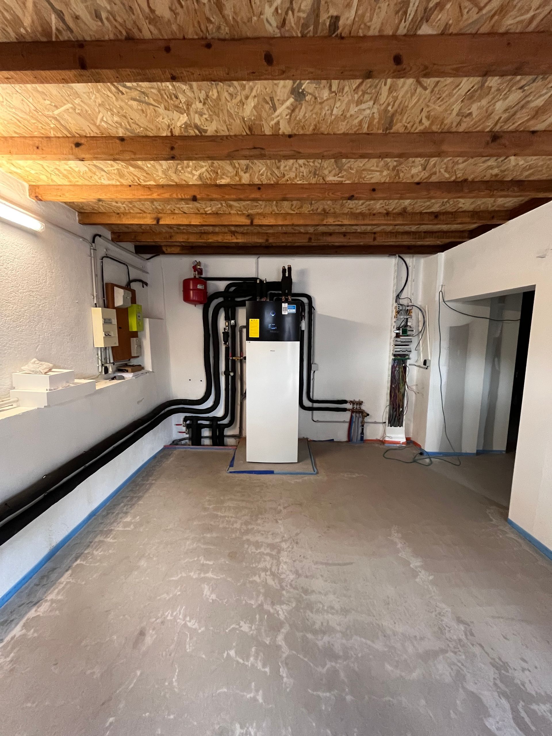 Sous-sol avec chauffage, plafond en bois. Murs blancs, sol en béton.