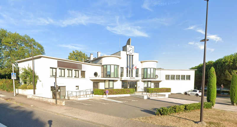 Bâtiment de la mairie avec tour de l'horloge, extérieur blanc, parking, rue, ciel bleu.
