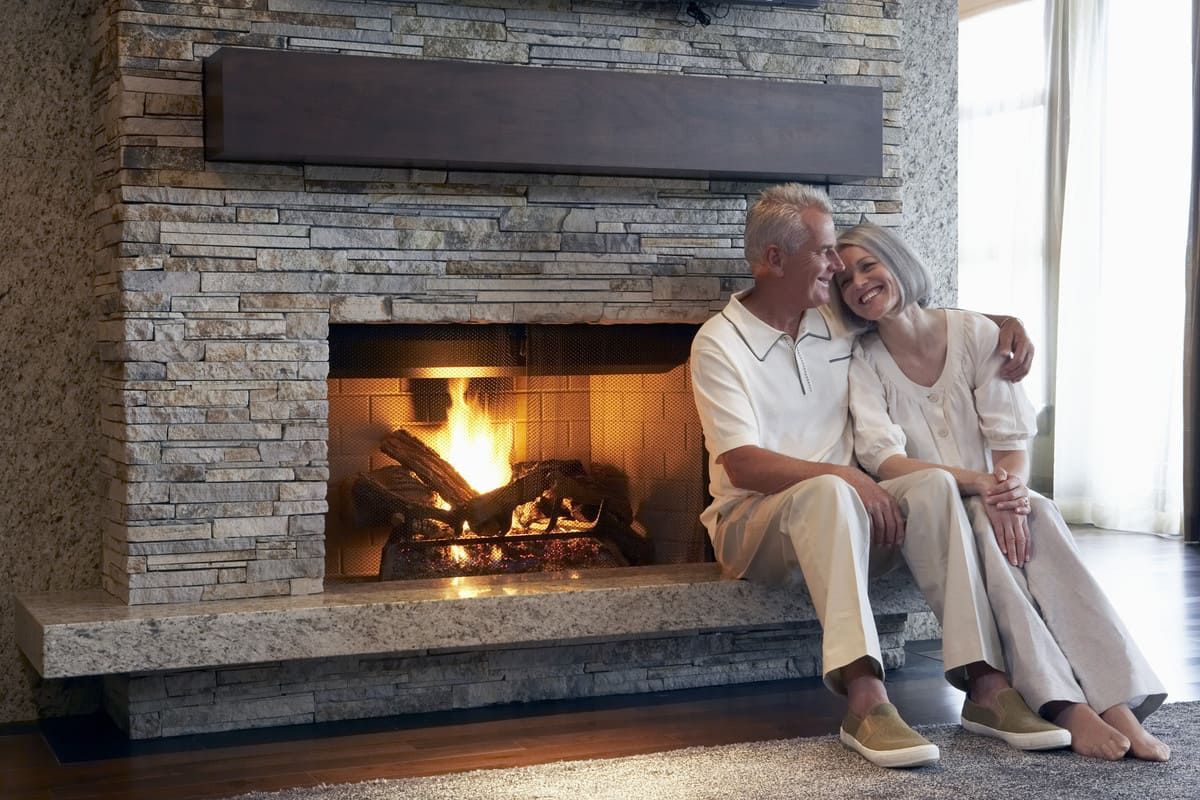 couple de seniors assis sur le rebord d'une cheminée