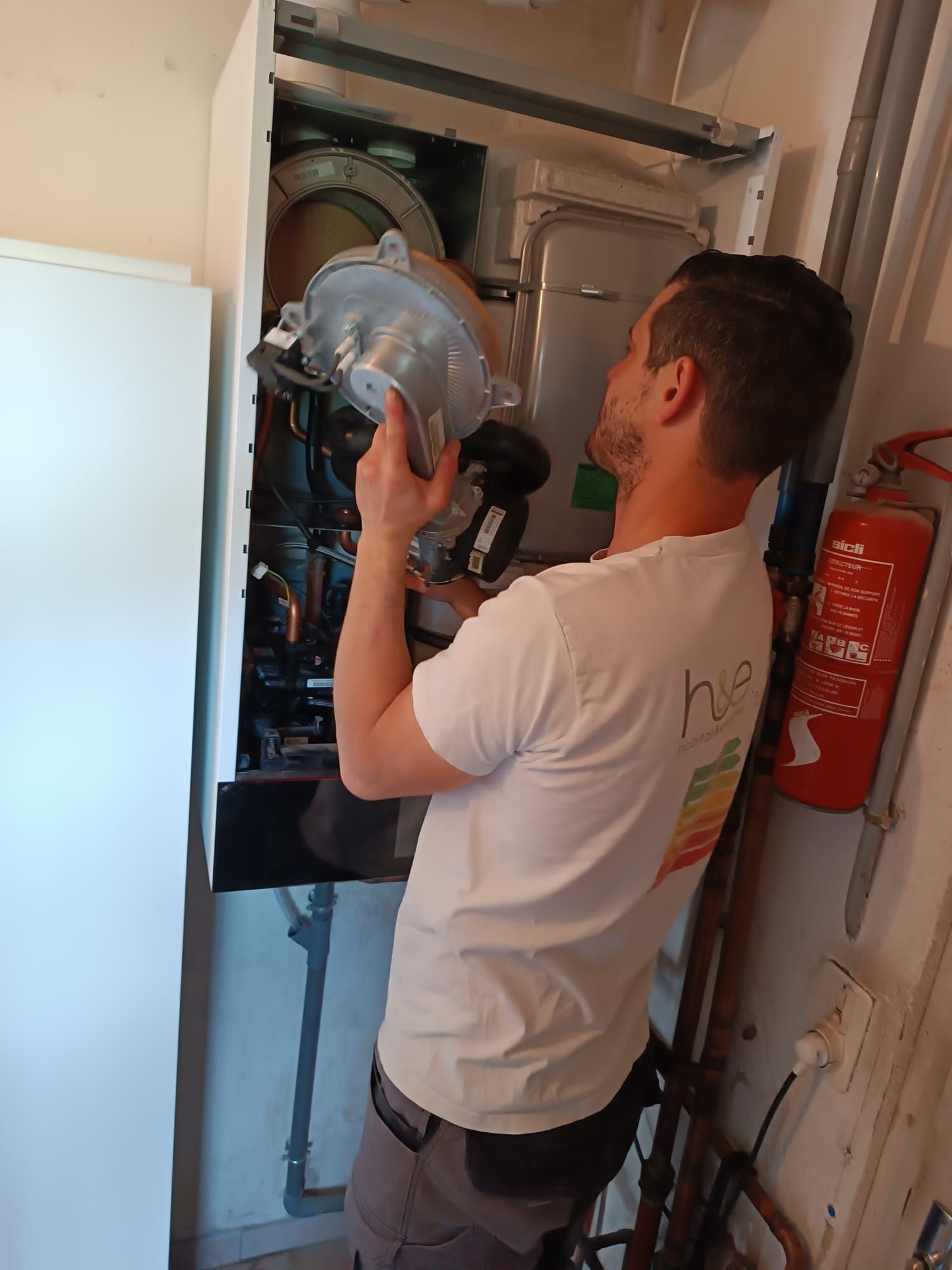 Un homme en chemise blanche travaille sur un four. Il tient une pièce à l'intérieur de l'appareil.